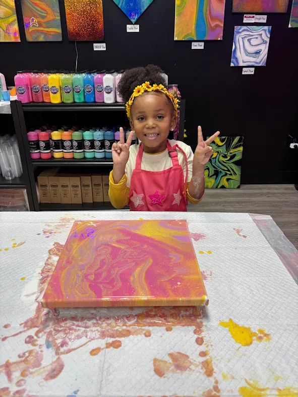 A proud young artist holding her custom fluid art creation