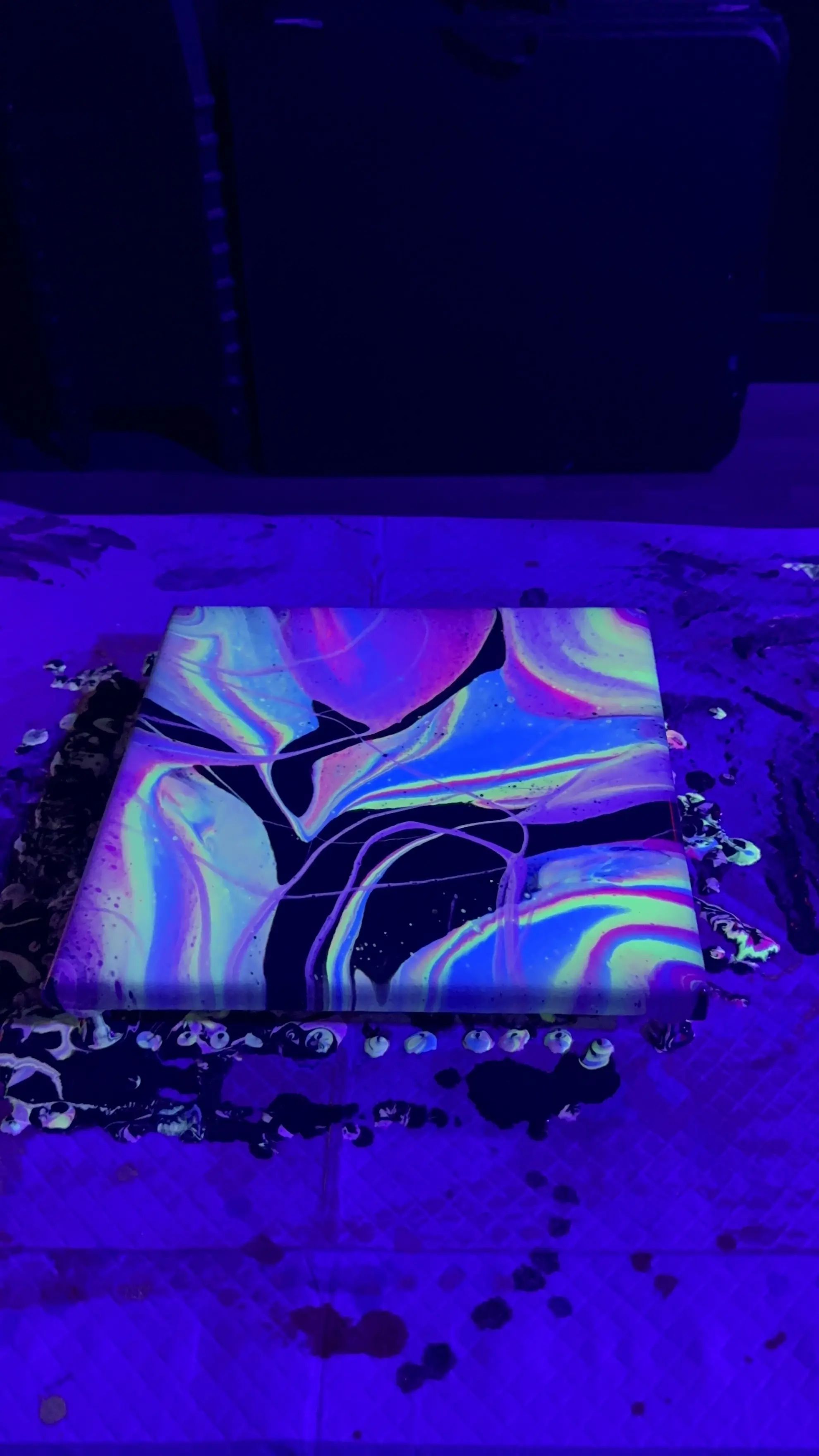 Vibrant neon paints glowing under UV light in a dark studio setting