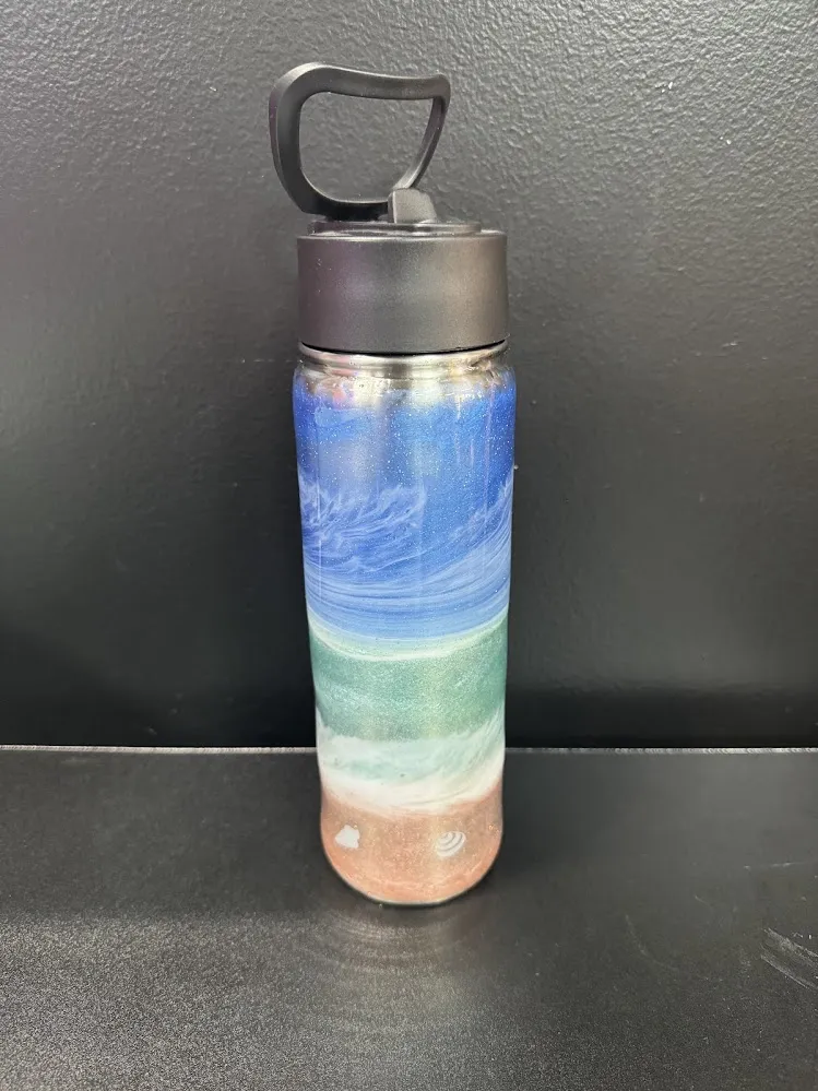 Adult designing a custom resin water bottle at Hawaii Fluid Art in Johns Creek